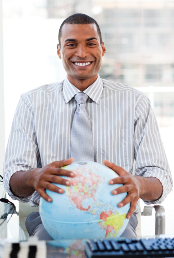 Enthusiastic businessman showing a terrestrial globe in his office