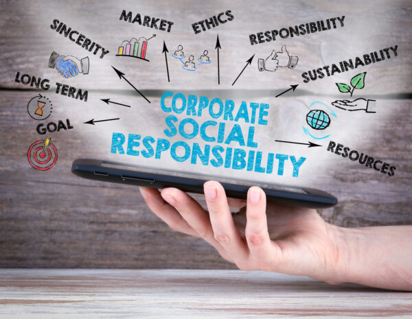 Corporate Social Responsibility Concept. Tablet computer in the hand. Old wooden background.