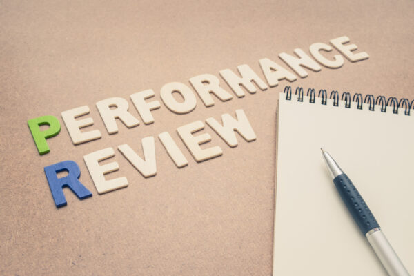Performance review text with open spiral notebook and pen on brown background - concept of quality measurement